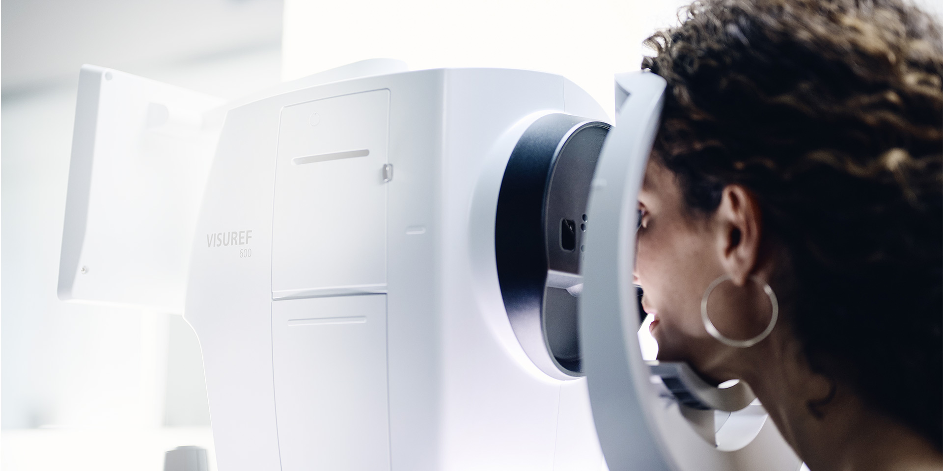 Nainen katsoo ZEISS VISUREF 600 -laitteen läpi
