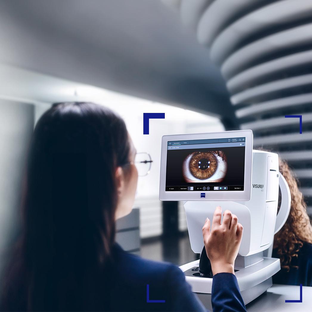 Naisoptikko katsoo ZEISS VISUREF 600 -laitteen näyttöä, jolla näkyy kuva silmästä.