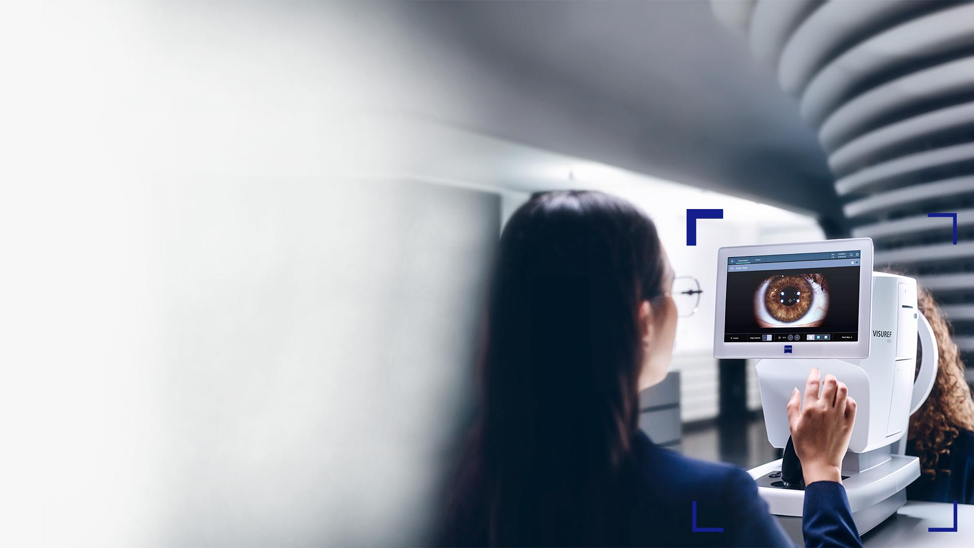 Naisoptikko katsoo ZEISS VISUREF 600 -laitteen näyttöä, jolla näkyy kuva silmästä.