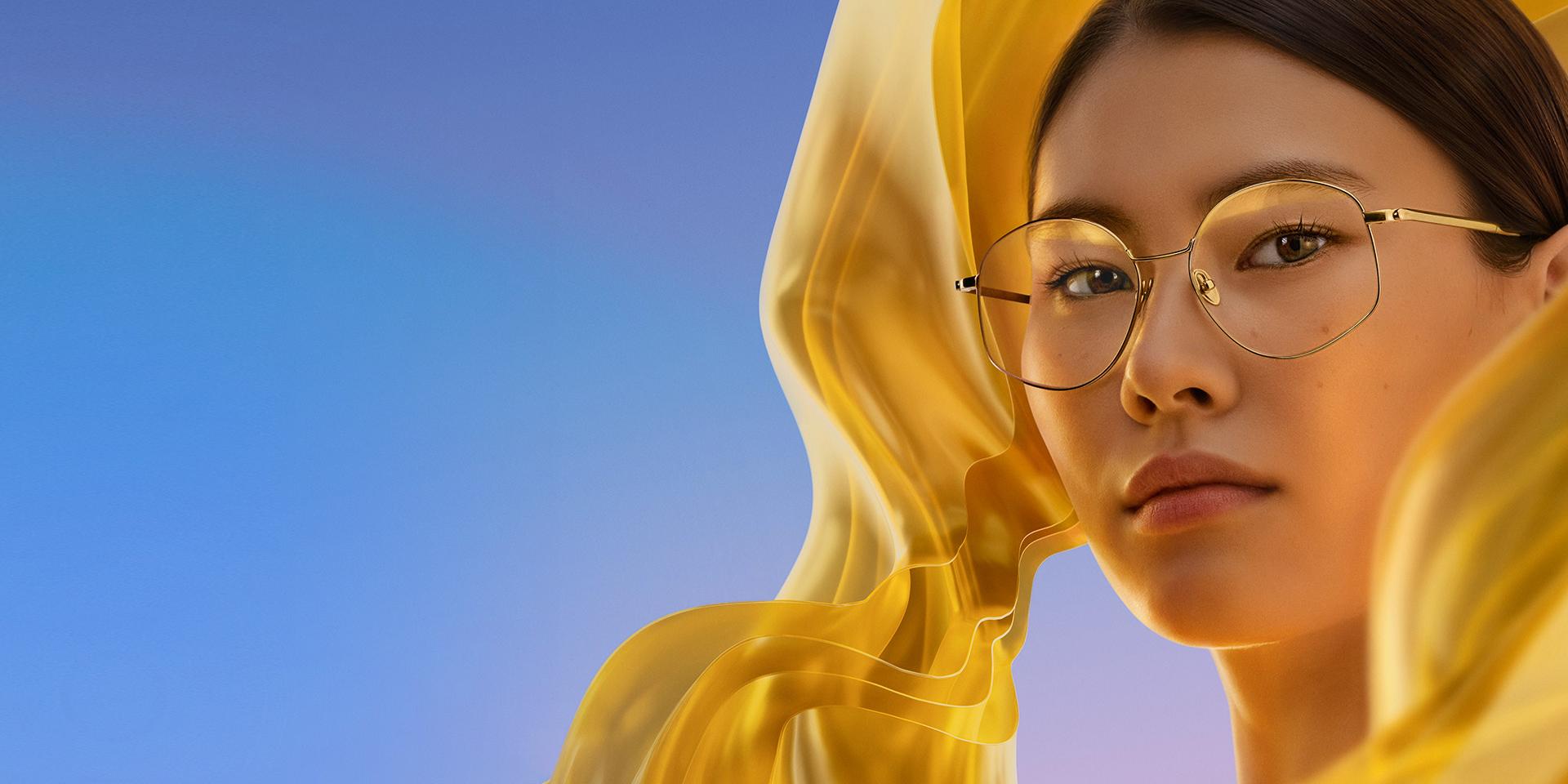 Nainen, jonka silmälasien ZEISS DuraVision Gold UV -pinnoite antaa linsseihin hienovaraisen mutta erottuvan kultaisen heijasteen.