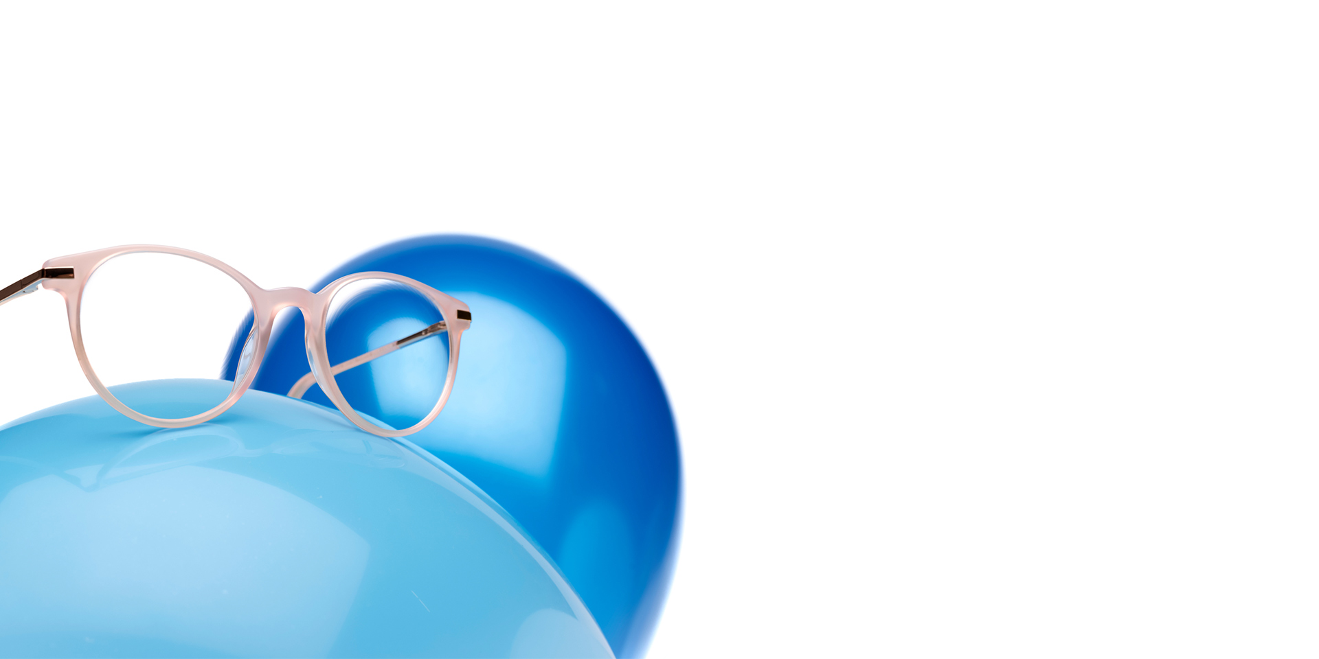 ZEISS MyoCare -linssit roosabeigeissä kehyksissä näkyvät vaaleansinisessä ilmapallossa. Taustalla on toinen hieman tummemman sininen ilmapallo.