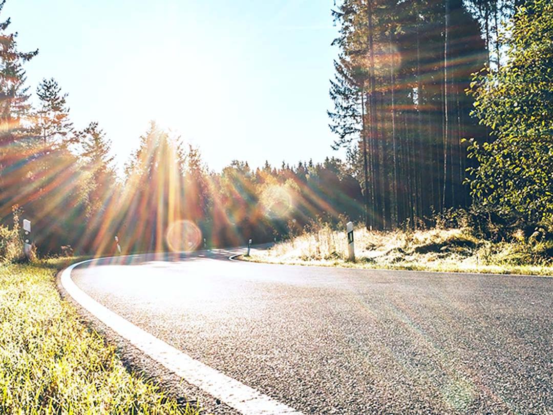 Liukukuva, jonka toisella puoliskolla on metsätie ja kirkas auringonvalo. Toisella puolella on sama tie, mutta vähemmän häikäisyä ja vahvemmat kontrastit. Kuva korostaa polarisoivien aurinkolasilinssien vaikutusta.