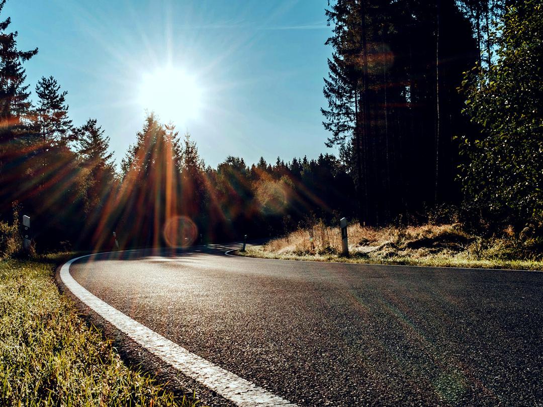 Liukukuva, jonka toisella puoliskolla on metsätie ja kirkas auringonvalo. Toisella puolella on sama tie, mutta vähemmän häikäisyä ja vahvemmat kontrastit. Kuva korostaa polarisoivien aurinkolasilinssien vaikutusta.
