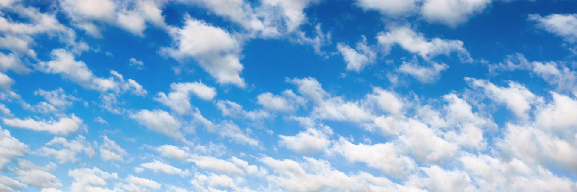 Panoraamakuva untuvan valkoisista pilvistä sinisellä taivaalla