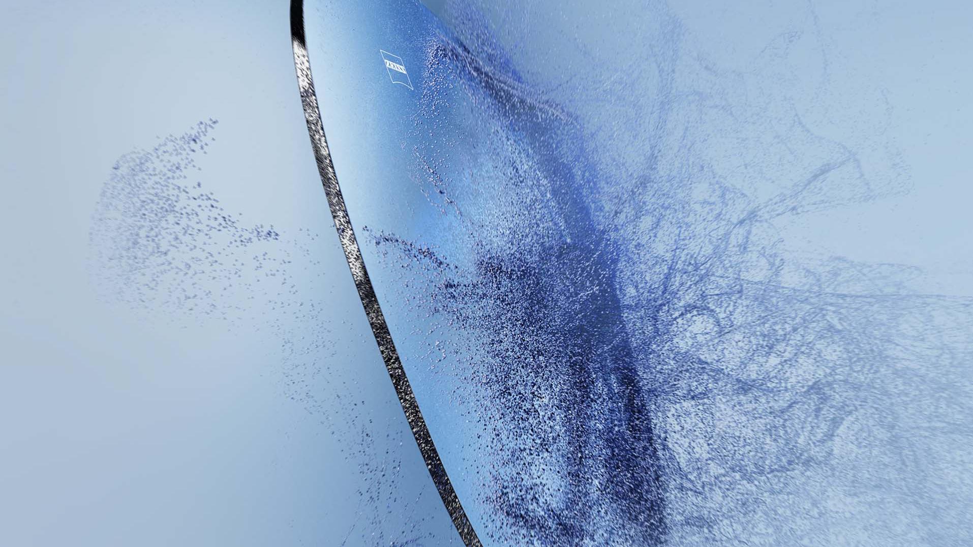 Hiekka osuu silmälasilinssiin, jossa on ZEISS-logo.