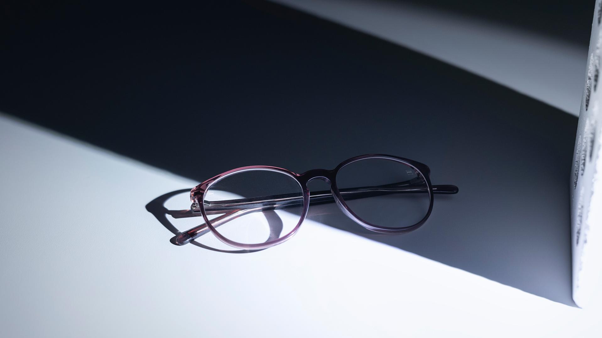 Puoliksi varjossa ja puoliksi auringossa olevat silmälasit, joissa on ZEISS-linssit ja DuraVision® -pinnoitteet.
