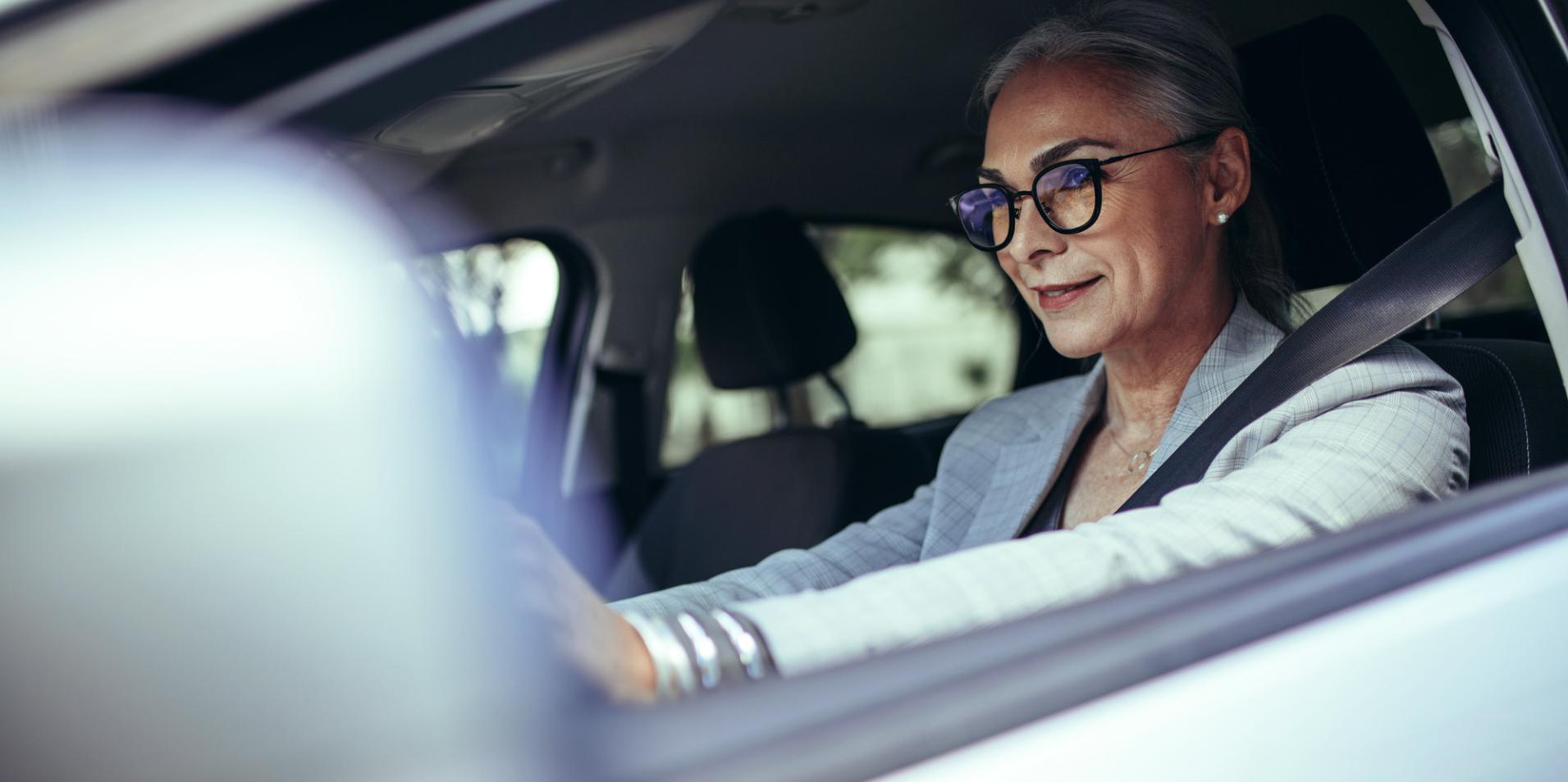 Autossa istuva aikuinen nainen, jolla on silmälasit ja ZEISS DriveSafe -linssit.