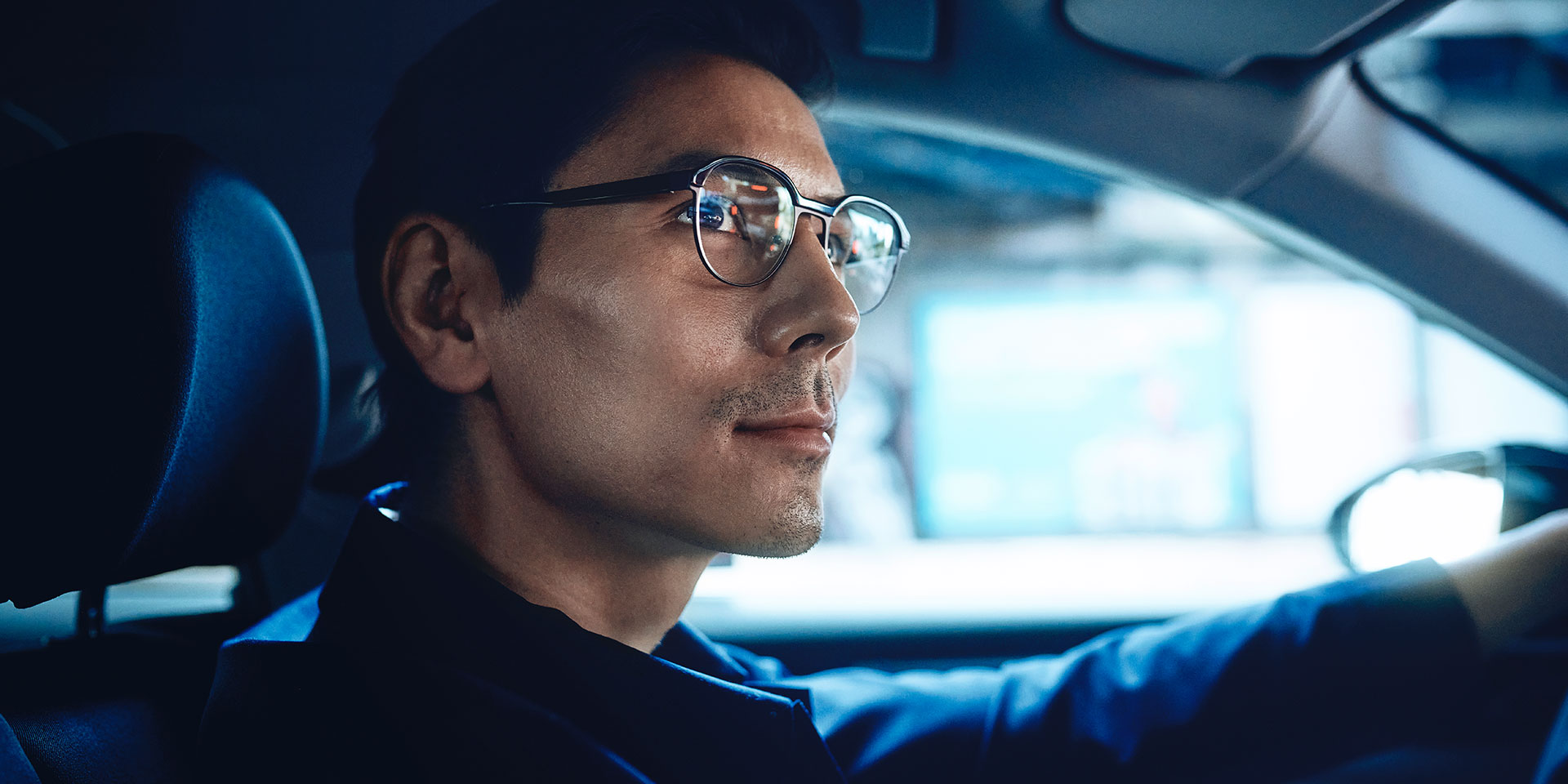 Mies ajaa autoa katsoen tietä itsevarmasti hieman hymyillen. Hän käyttää ZEISS DriveSafe single vision -linssejä.