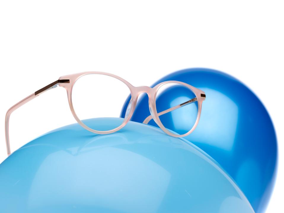 ZEISS MyoCare -linsseillä varustetut vaaleanpunaiset silmälasikehykset sinisen ilmapallon päällä.