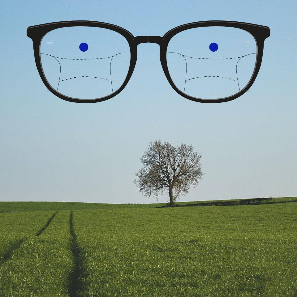 Kehykset, joissa on progressiiviset moniteholinssit ja viivat, jotka kuvaavat eri näköalueita. Linssin eri osat on korostettu: kaukonäön alue – silmälasien yläosa.
