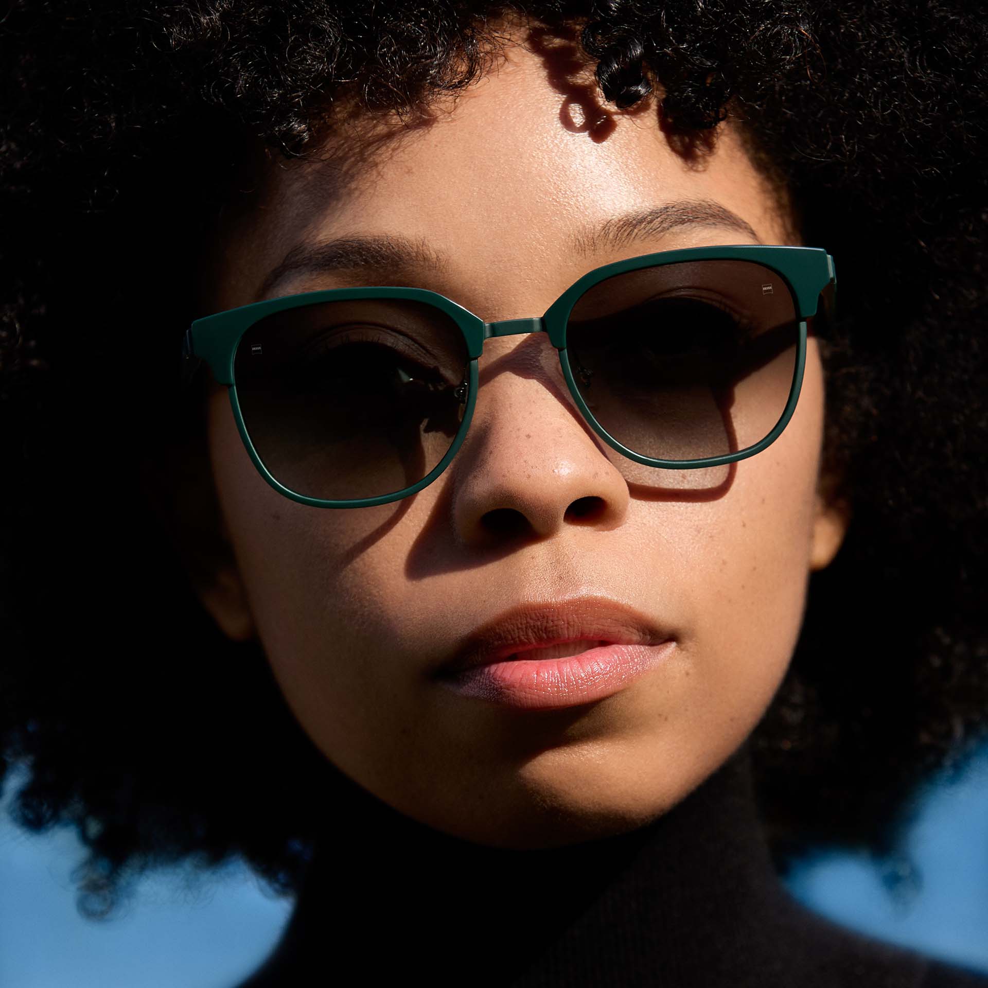 Nainen, jolla on vihreät kehykset ja liukuväriset linssit. 